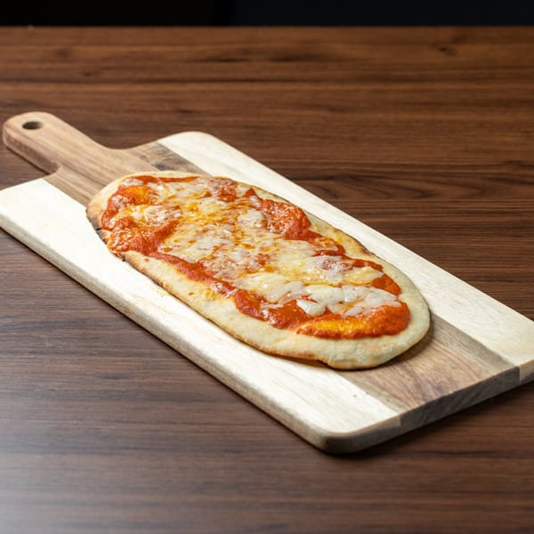 A rectangular flatbread pizza with melted cheese and red sauce on a two-toned wooden serving board.